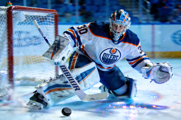 NHL比赛中，油人队守门员在扑救过程中全力封堵射门的瞬间